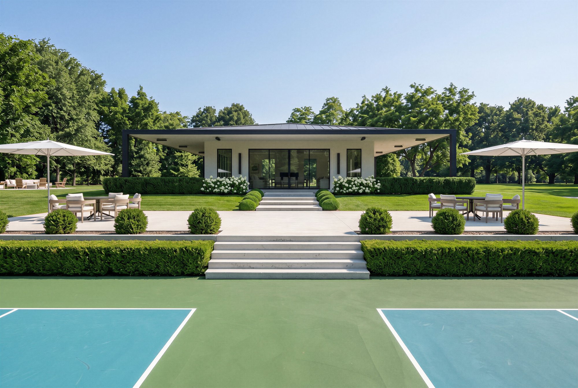Clubhouse rear terrace with umbrella-shaded dining sets flanking the steps that descend to the pickleball courts