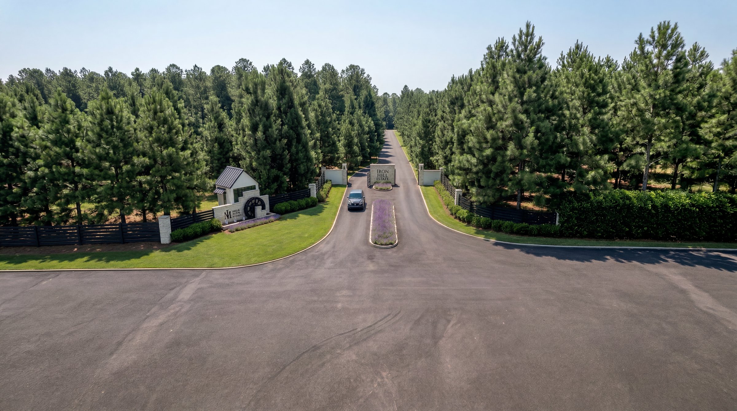 Aerial view of the Iron Mill Estates gated entrance, a single controlled drive between long walls of mature pines
