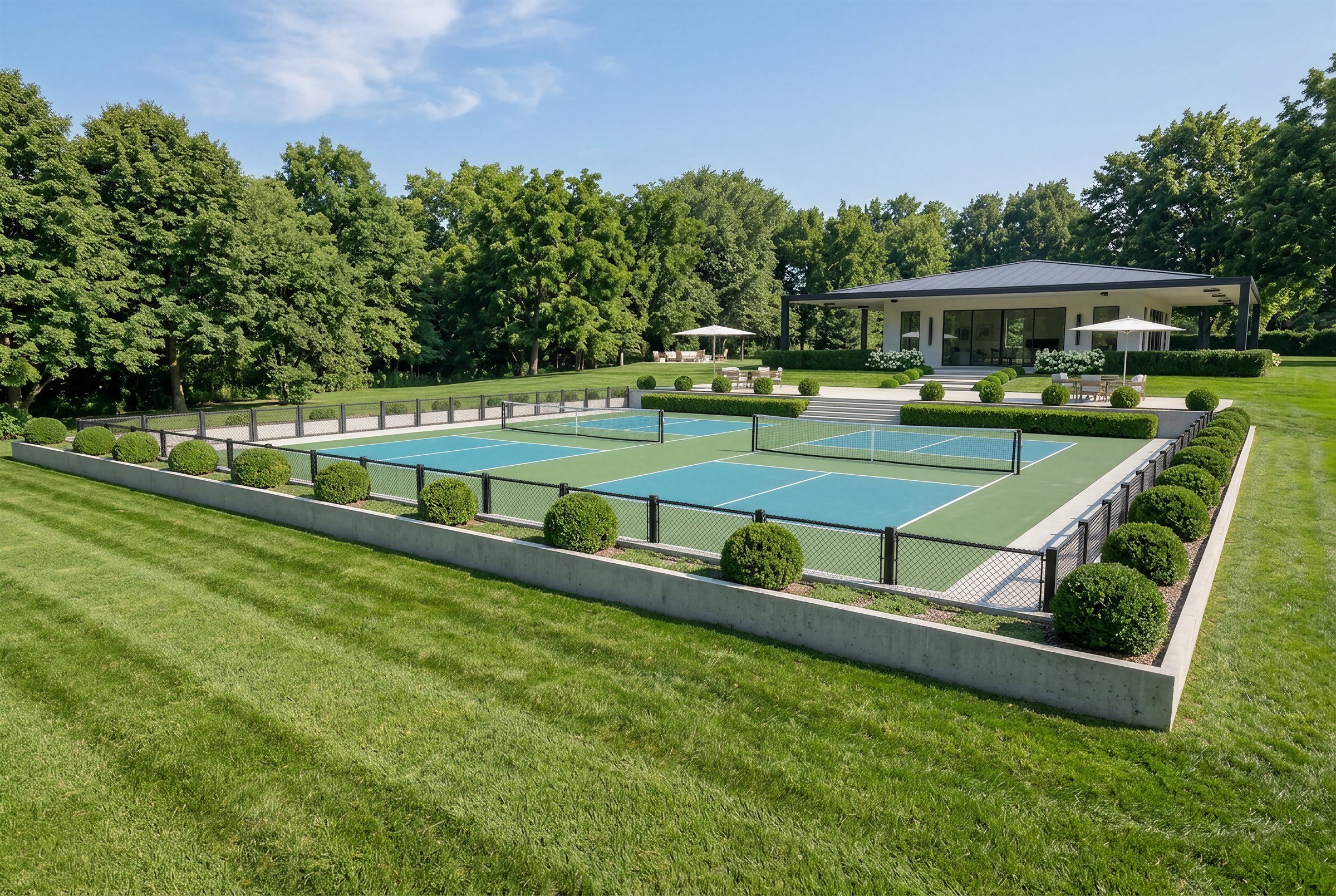 Two pickleball courts and the clubhouse framed by hedges and boxwoods